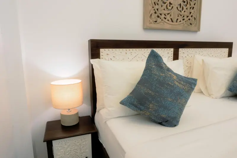 Un lit avec des oreillers et une lampe de chevet sur une table.
