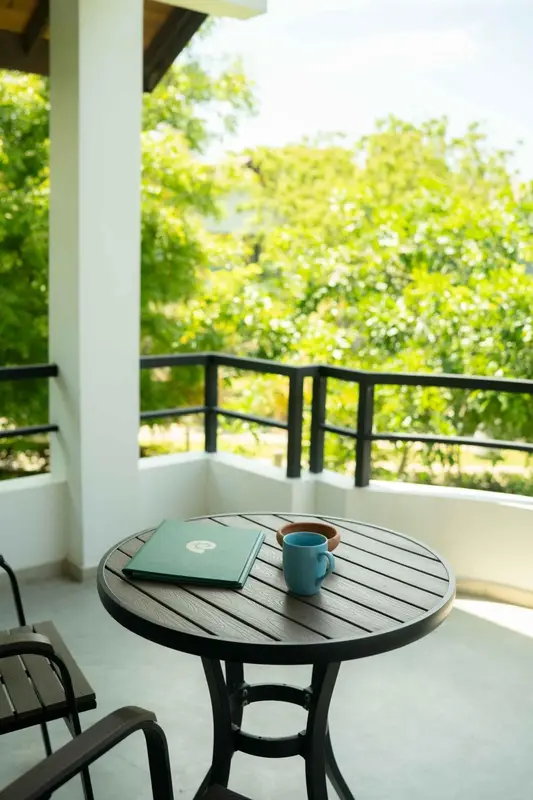 Une table ronde avec un livre et une tasse sur une terrasse ensoleillée.