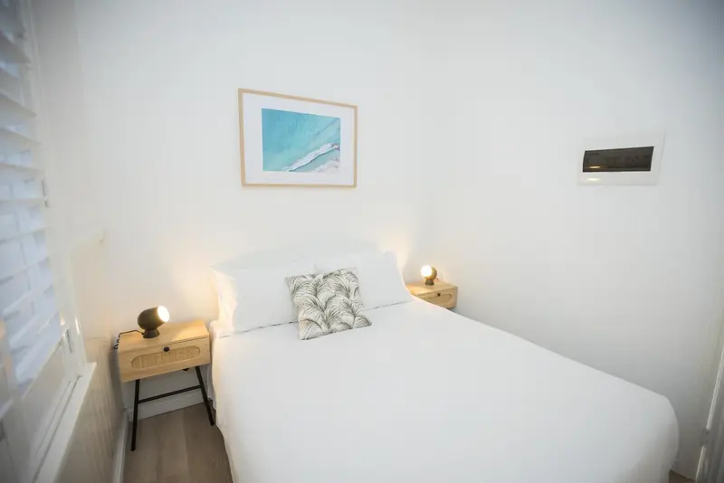 Une chambre lumineuse avec un lit recouvert de linge blanc.