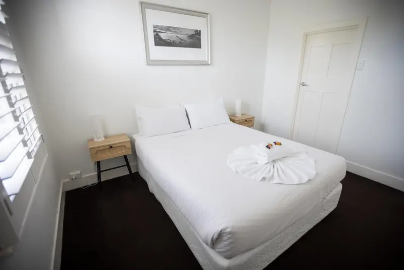 Une chambre lumineuse avec un lit recouvert de linge blanc.