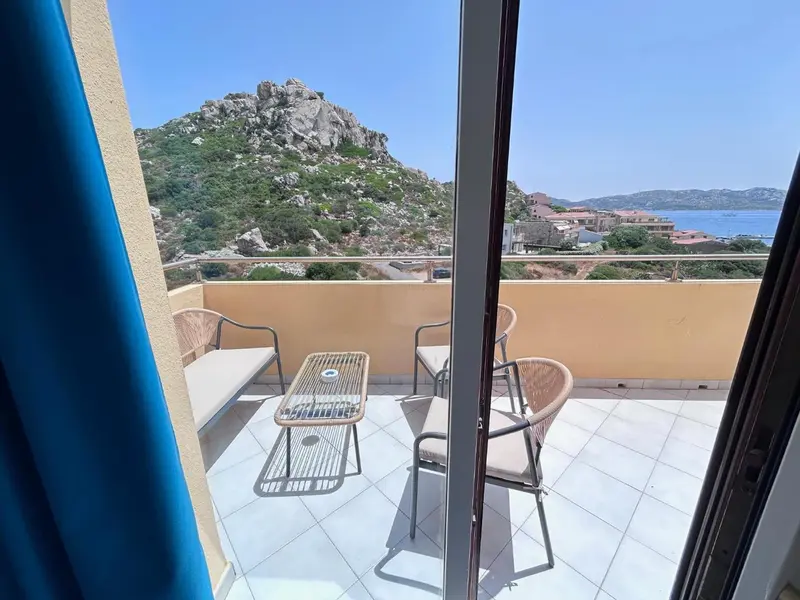 Terrasse carrelée avec mobilier en osier donnant sur une vue côtière.