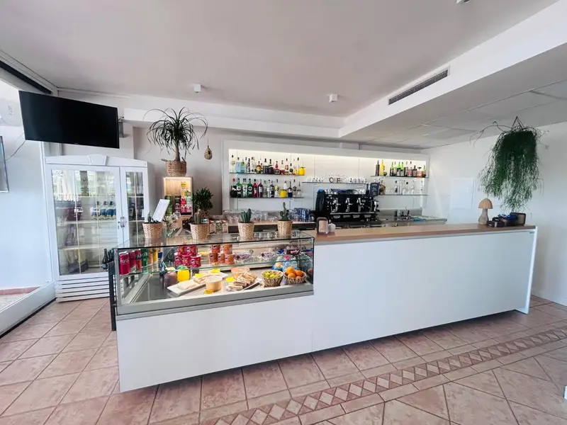 Un comptoir de bar blanc avec des bouteilles et des collations exposées.