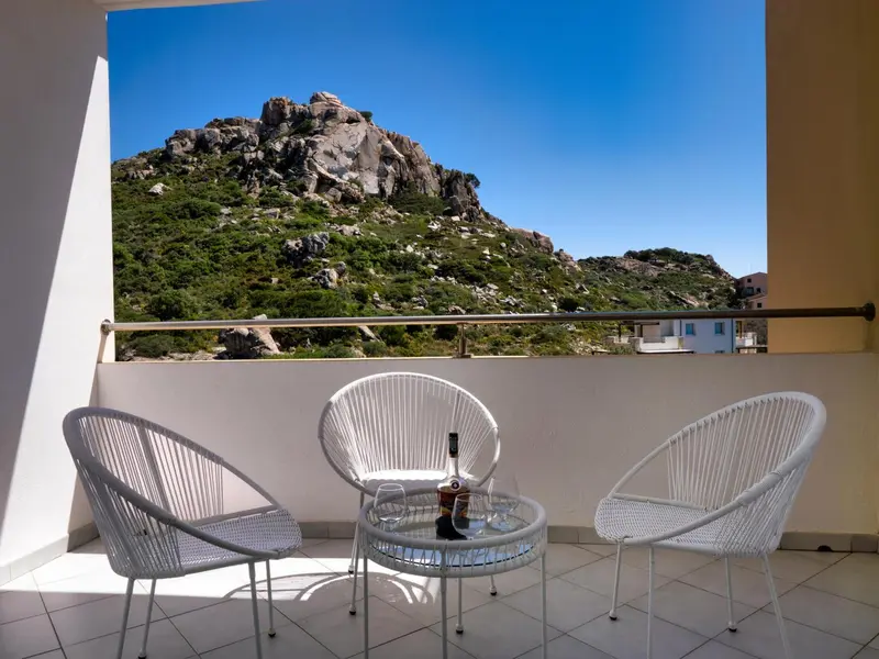 Terrasse avec mobilier blanc et vue sur une colline.