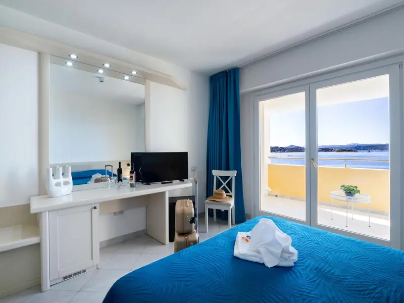 Une chambre lumineuse avec un lit fait et une vue sur la mer.