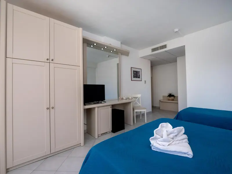 Une chambre lumineuse avec un lit recouvert d'une couverture bleue et un grand placard.