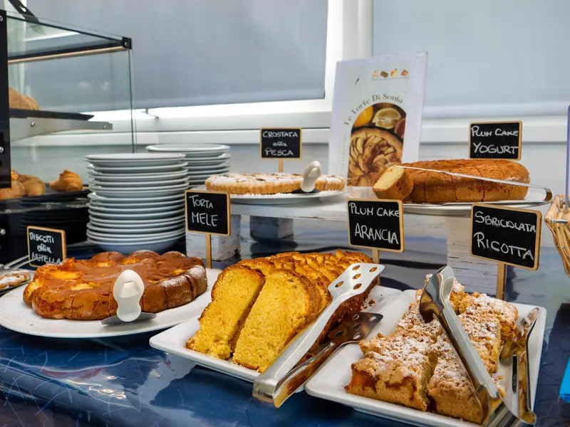 Présentation de pâtisseries variées sur un comptoir réfrigéré.