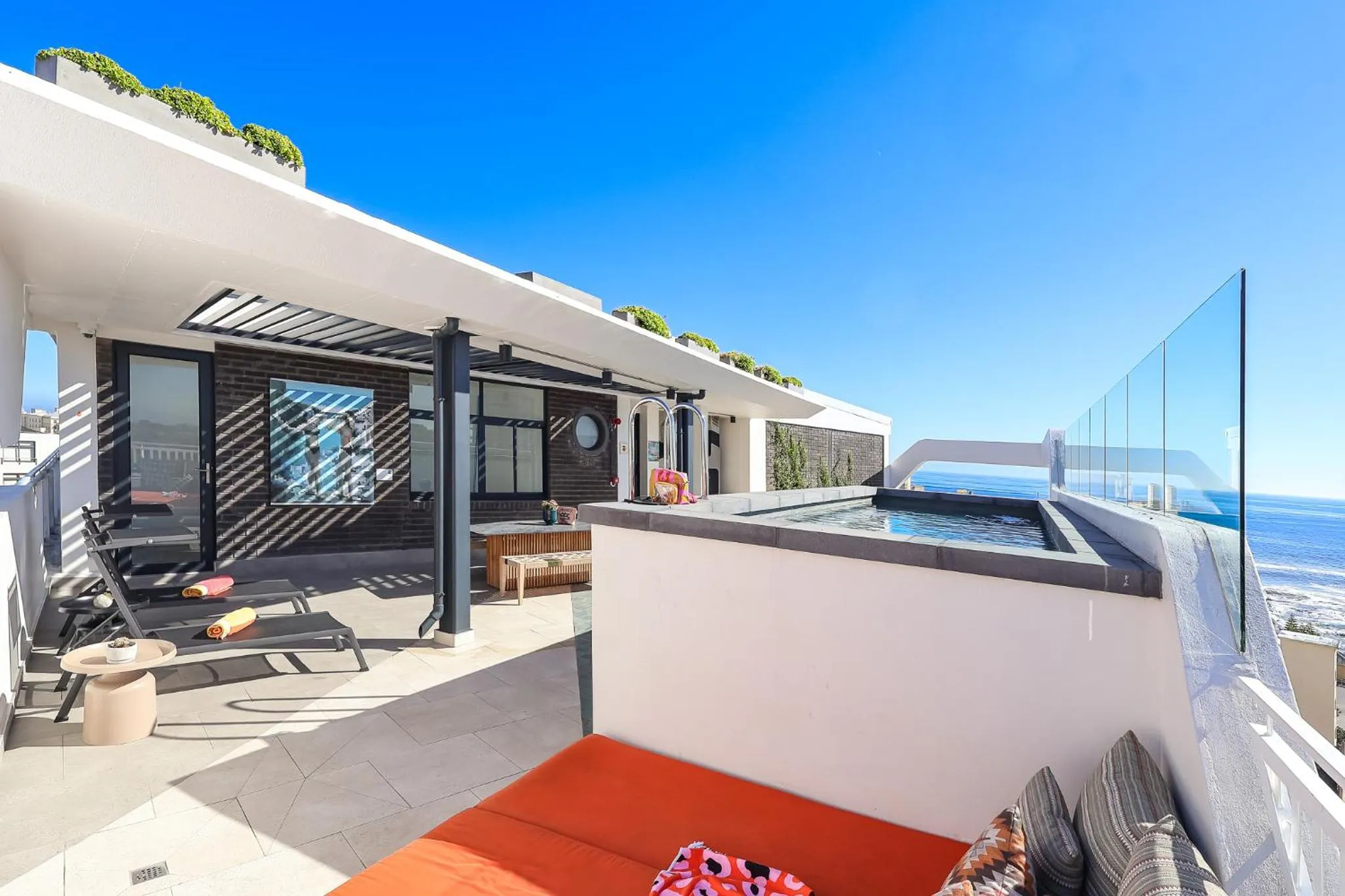 Terrasse aménagée avec transats et jacuzzi, vue sur la mer.