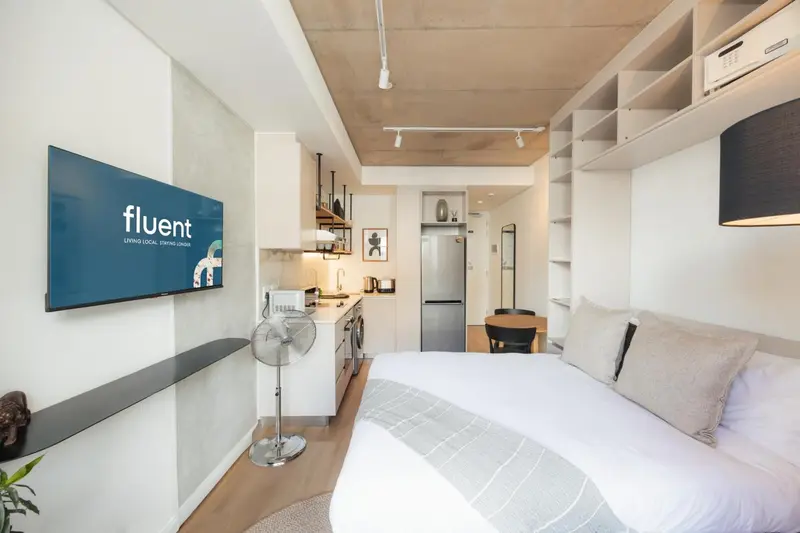 Une chambre lumineuse avec un lit et un espace cuisine.
