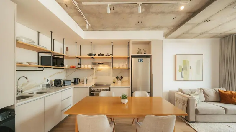 Une cuisine moderne avec une table à manger en bois et un canapé gris.