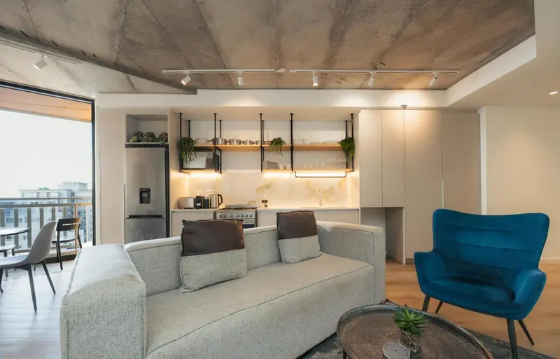 Un salon moderne s'ouvre sur une cuisine équipée et un espace repas.