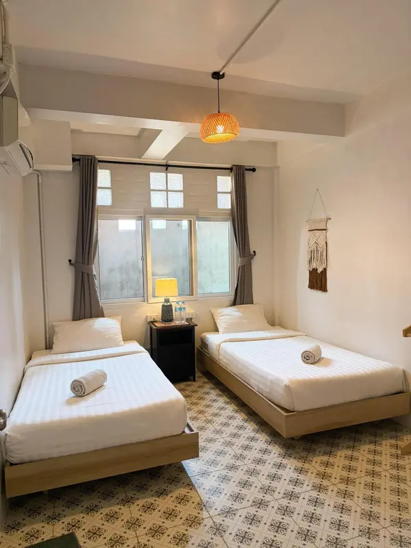 Une chambre lumineuse avec deux lits simples et une décoration murale.