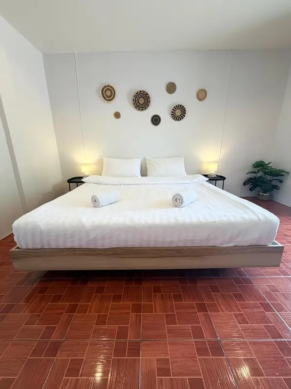 Une chambre lumineuse avec un grand lit recouvert de linge blanc et des décorations murales.