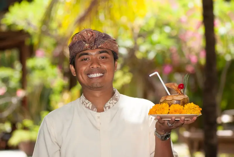 Un homme souriant présente un plat décoré de fleurs et de fruits.
