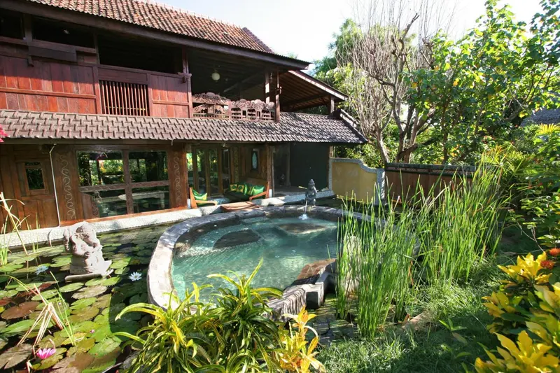 Bâtiment en bois sombre avec piscine et végétation luxuriante.