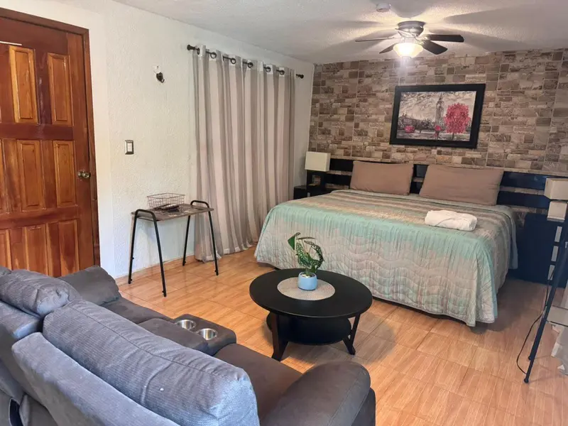 Une chambre avec un canapé, une table basse et un lit recouvert d'une courtepointe.