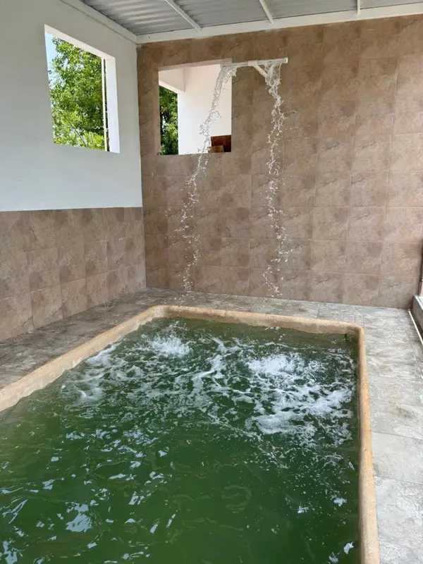 Bassin extérieur avec jets d'eau et carrelage mural.