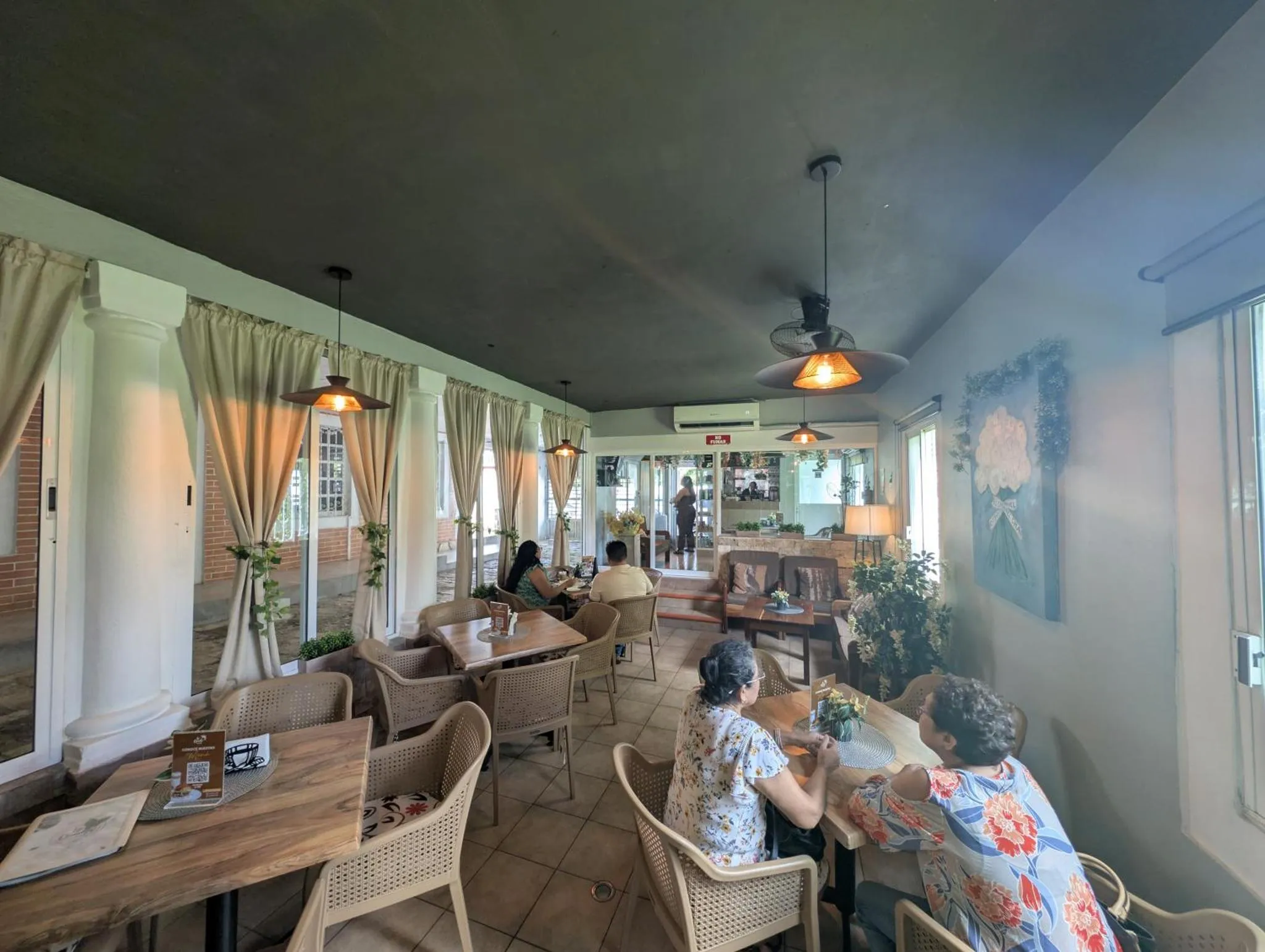 Une salle lumineuse avec des tables et des chaises où des clients prennent leur repas.