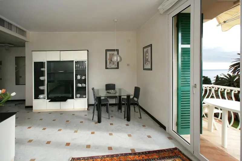 Une salle à manger lumineuse s'ouvre sur un balcon avec vue sur la mer.