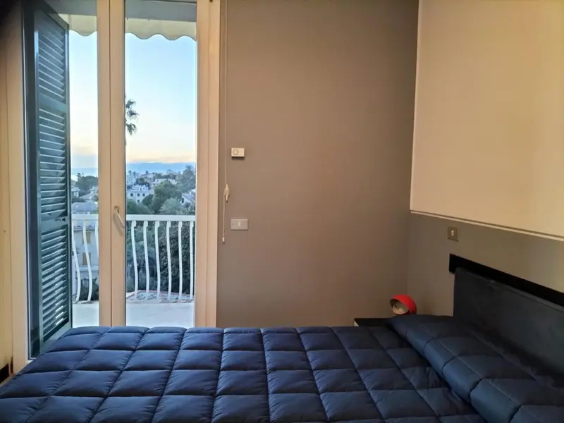 Une chambre avec un lit donnant sur un balcon et une vue sur la ville.