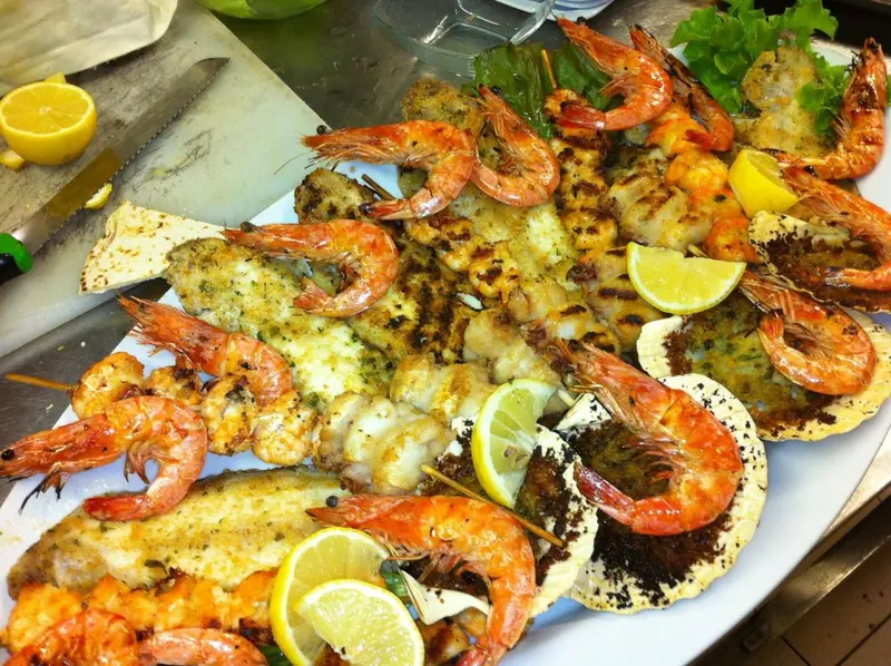 Assortiment de fruits de mer grillés et de poissons servis avec des quartiers de citron.