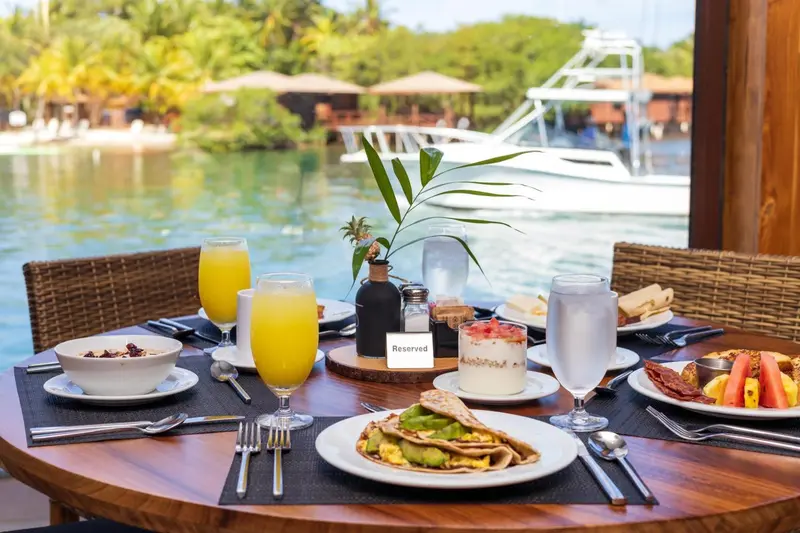 Une table est dressée pour le petit-déjeuner avec des plats variés et des boissons.