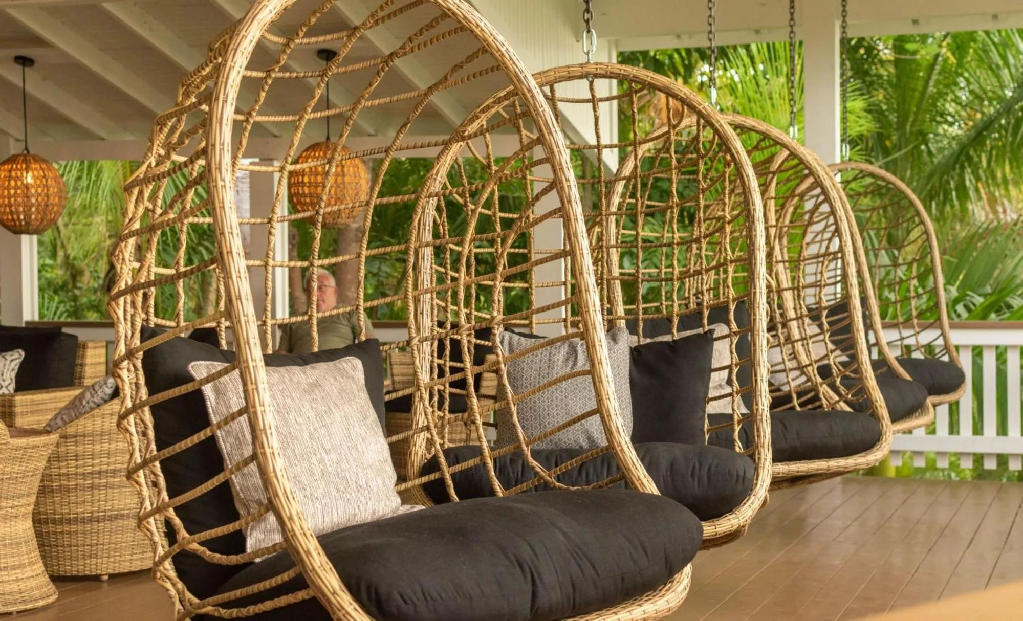 Des fauteuils suspendus en osier invitent à la détente sur une terrasse ombragée.