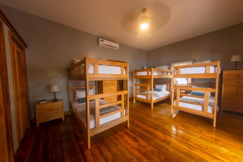 Une chambre avec plusieurs lits superposés en bois clair.
