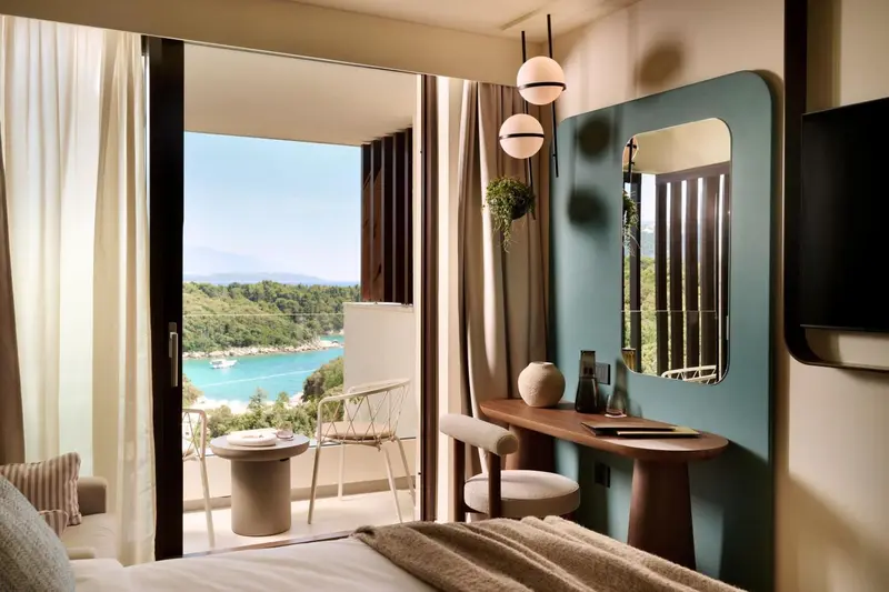 Une chambre lumineuse s'ouvre sur une vue dégagée sur la mer et la végétation.