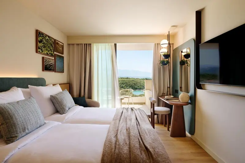 Chambre lumineuse avec un grand lit et une vue sur la mer.