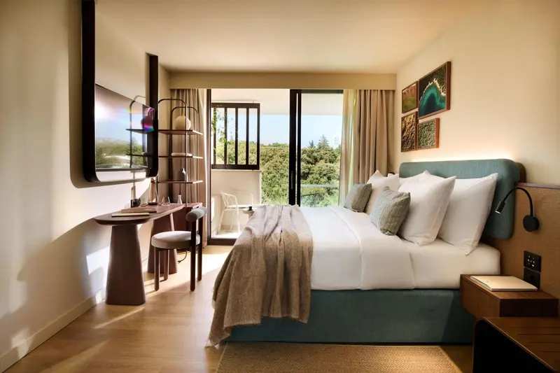 Une chambre lumineuse avec un grand lit et un accès à une terrasse verdoyante.