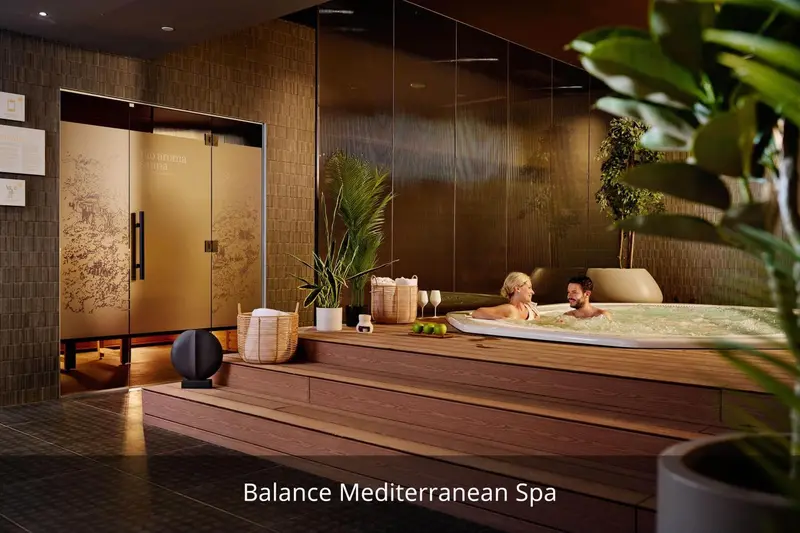 Un couple se détend dans un jacuzzi intérieur avec des plantes tropicales.