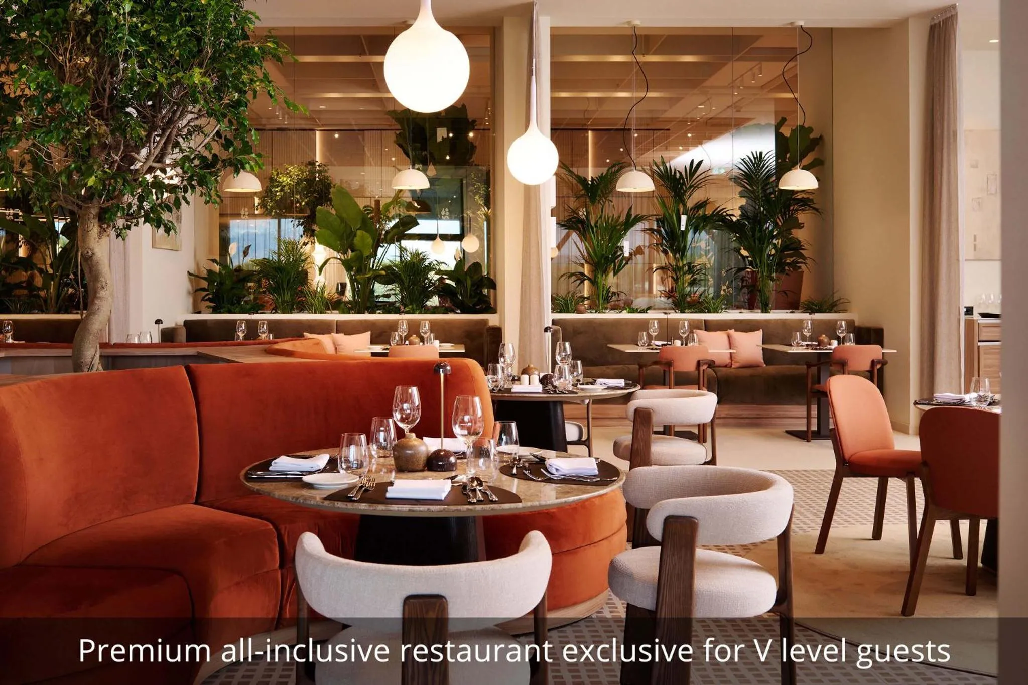 Une salle de restaurant lumineuse avec des tables rondes et des banquettes en velours.