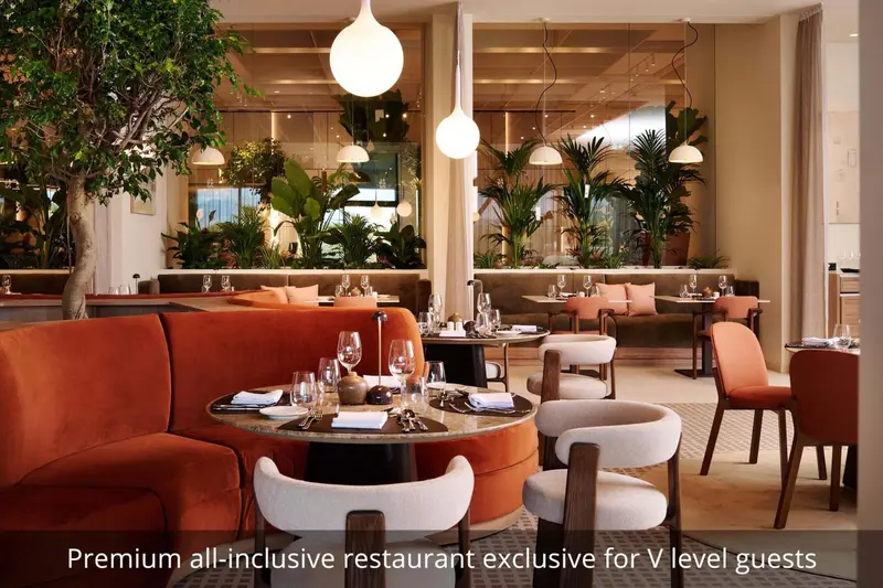 Une salle de restaurant lumineuse avec des tables rondes et des banquettes en velours.