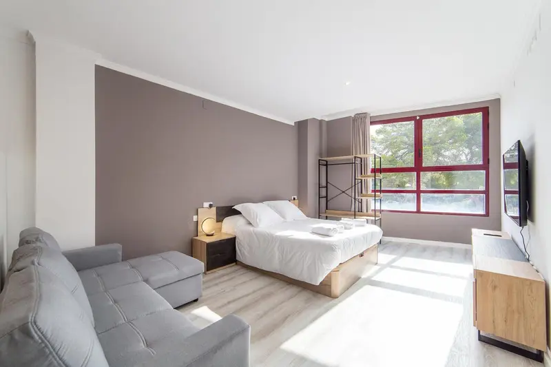 Une chambre lumineuse avec un canapé et un lit double.