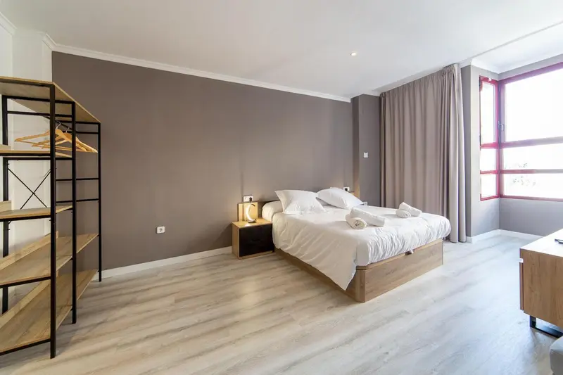 Une chambre lumineuse avec un grand lit et un portant à vêtements.