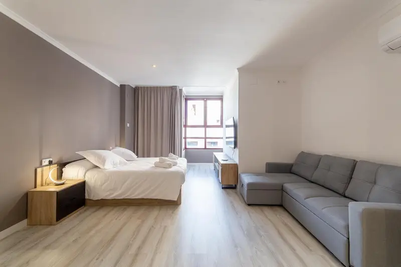 Espace de vie lumineux avec un lit et un canapé d'angle.
