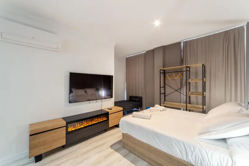 Une chambre lumineuse avec un grand lit et un téléviseur mural.
