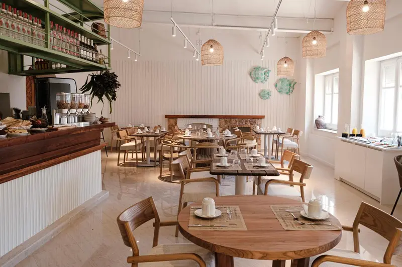 Une salle lumineuse avec des tables en bois et des suspensions en rotin.
