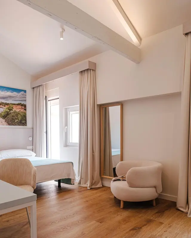 Une chambre lumineuse avec un lit et un fauteuil.