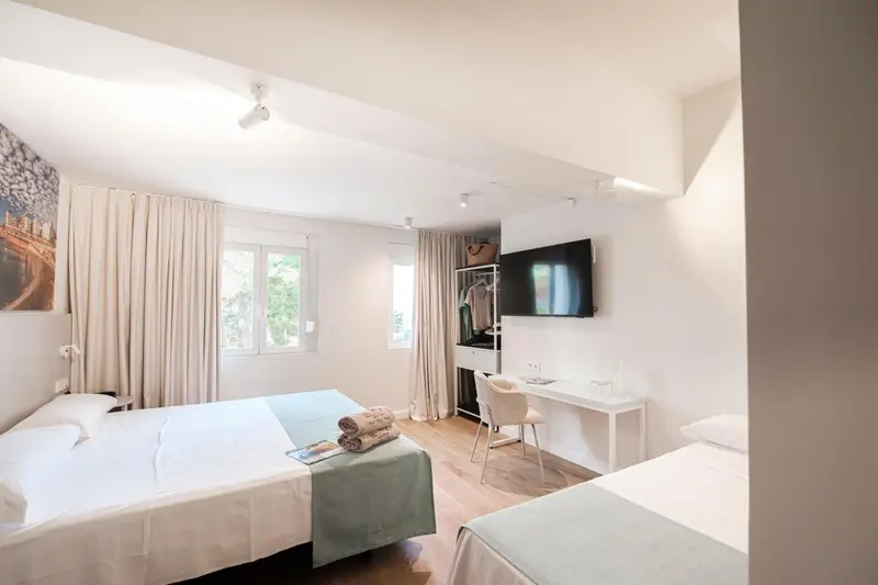 Une chambre lumineuse avec deux lits et un bureau.