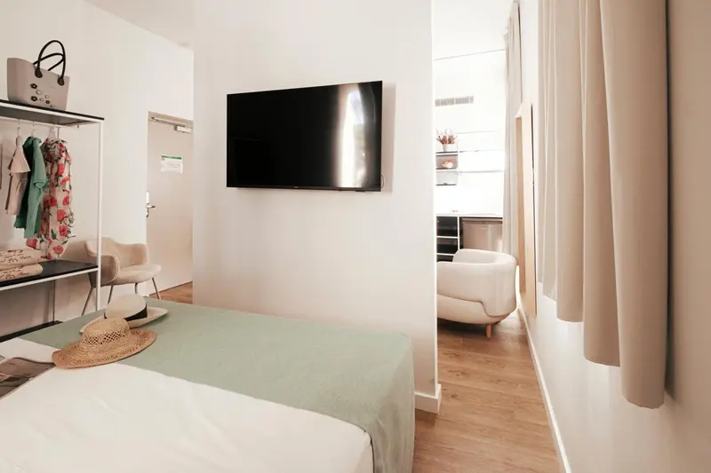 Une chambre lumineuse avec un lit et un téléviseur mural.