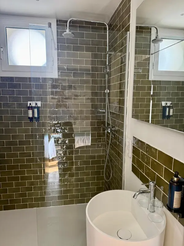 Une douche à l'italienne avec carrelage vert et vasque blanche.