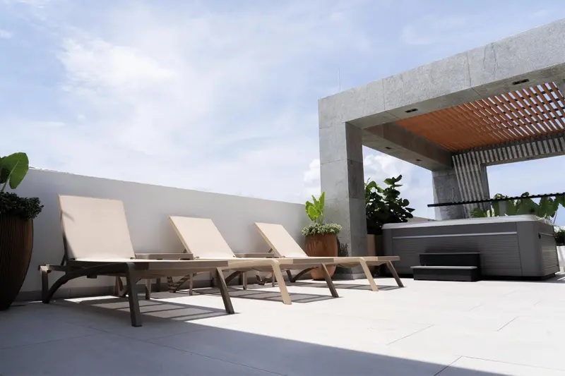 Transats alignés sur une terrasse ensoleillée avec un jacuzzi.