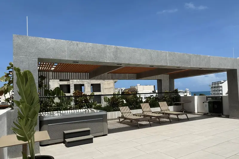 Terrasse aménagée avec transats et jacuzzi, surplombant un paysage urbain.