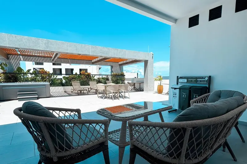 Espace de détente extérieur avec mobilier en rotin et pergola ombragée.