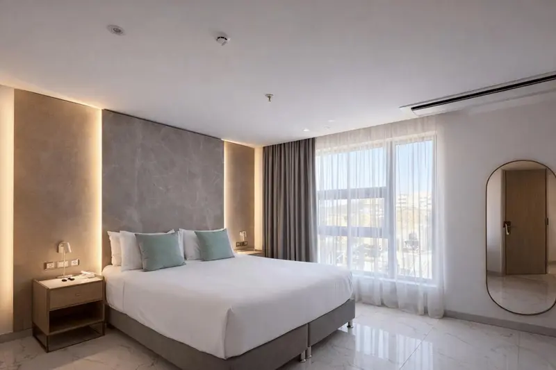 Chambre lumineuse avec un grand lit et une fenêtre.
