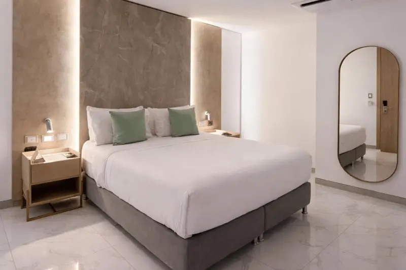 Une chambre lumineuse avec un grand lit et un miroir.