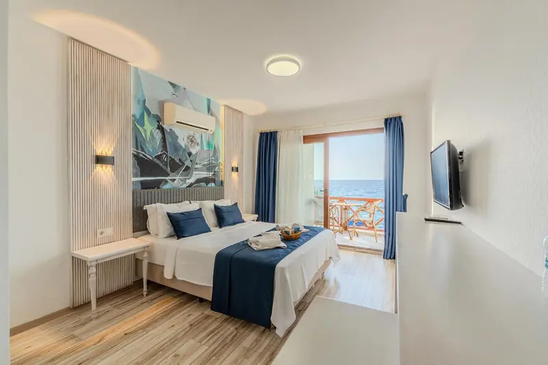 Une chambre lumineuse avec un lit double donnant sur une vue mer.