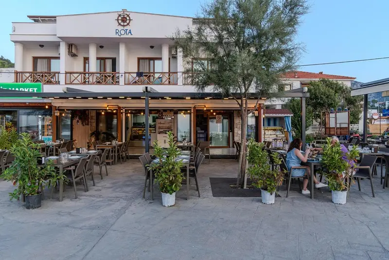 Terrasse de restaurant avec tables et végétation.