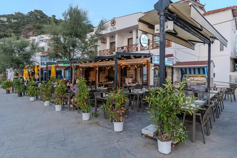 Terrasse de restaurant avec tables et chaises en bord de mer.